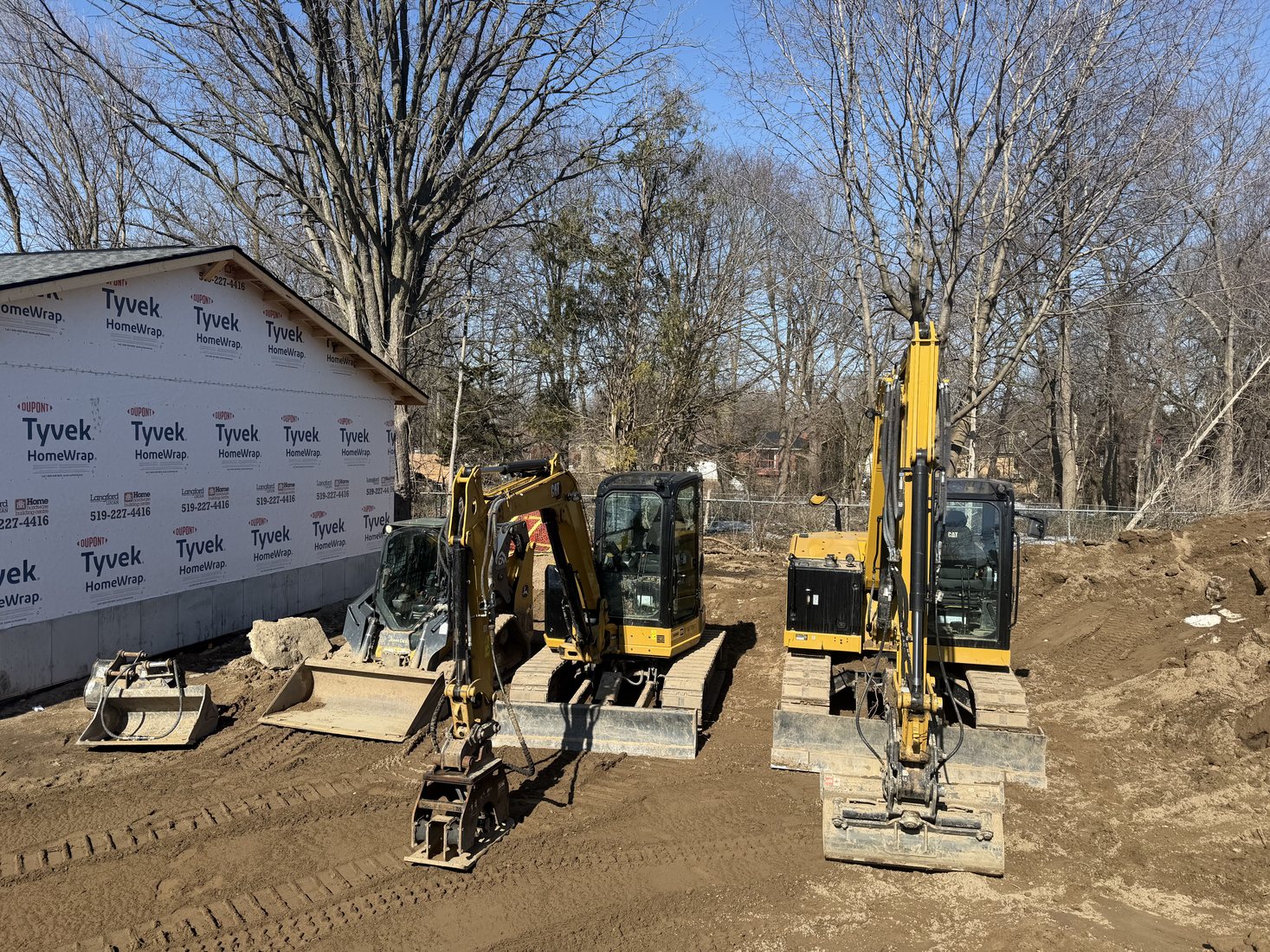 Equipment staged beside a building site with trees and cleared ground