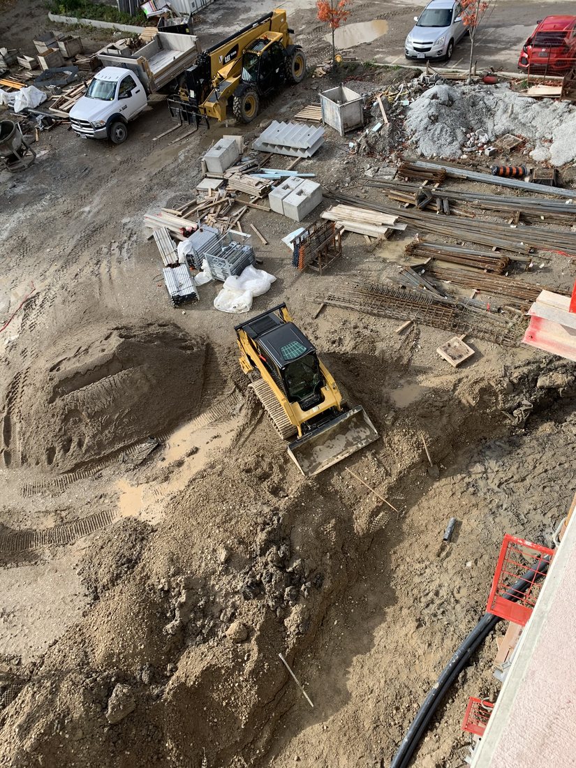 Skid steer and truck cleaning up construction and demolition material