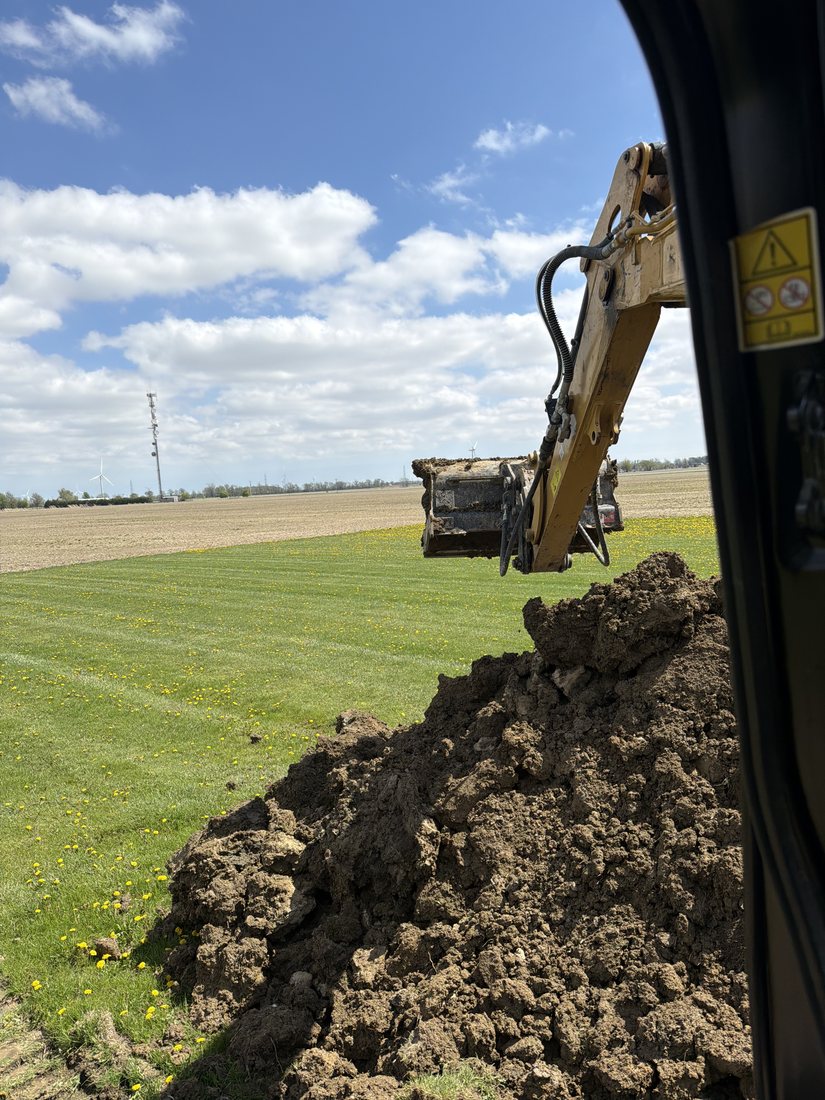Excavator trenching through a field