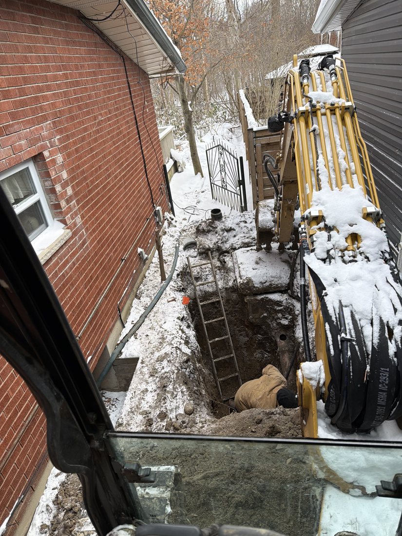 Excavator completing sewer repair work beside a home